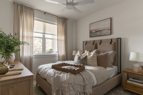 A bedroom with a large bed and a window with curtains.